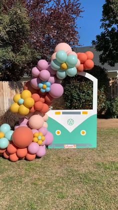 a vw camper decorated with balloons and flowers in front of a fenced yard