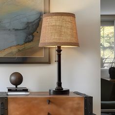 a lamp is sitting on top of a dresser in a room with a large painting