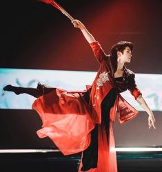 a woman in red and black dress dancing on stage