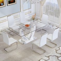 a glass dining table with white chairs and a chandelier hanging from the ceiling