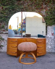 an old desk with a chair in front of it on the sidewalk next to a wall