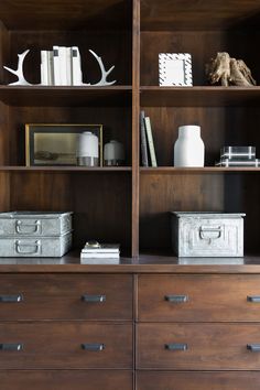 the bookshelf is full of many items and has deer antlers on it