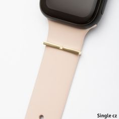 an apple watch with a gold band on it's side, sitting on top of a white surface