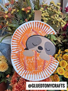 an orange and white paper plate with a slotty on it next to some flowers