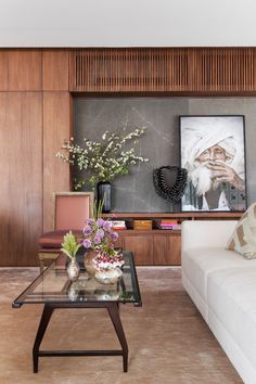 a living room filled with furniture and flowers on top of a glass table in front of a fireplace