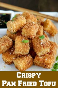 crispy pan - fried tofu on a plate with dipping sauce and chopsticks