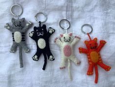 three keychains with cats on them sitting on a white cloth covered tablecloth