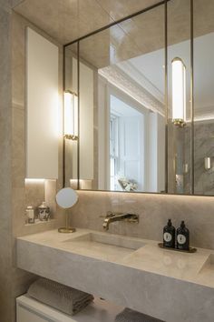 a bathroom with two sinks, mirrors and lights on the wall above it's counter