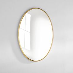 a white wall with a round mirror hanging on it's side and a window in the middle