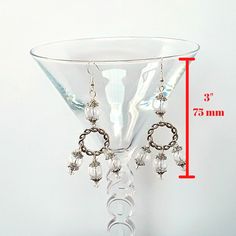 a clear glass vase with some dangling earrings on it's side and measurements for the base