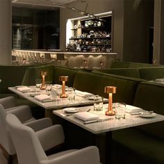 an empty restaurant with green booths and white table cloths, gold candlesticks on the tables