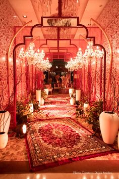 an elaborately decorated hallway with chandeliers and vases on the floor is lit by candles