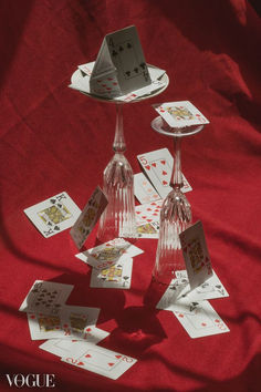 cards and wine glasses are arranged on a red tablecloth