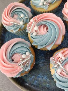 cupcakes with blue and pink frosting are on a plate next to silverware