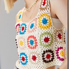 a woman wearing a crochet top with multicolored flowers on it