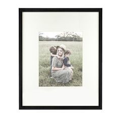 a woman and child are sitting in the grass with their arms around each other as they hug