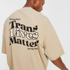 a man wearing a tan t - shirt with the words trans lives matter on it