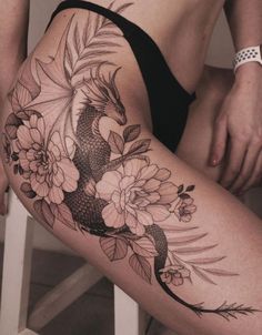 a woman's thigh with flowers and a koi fish tattoo on her leg