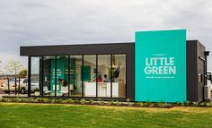 the little green store is on display in front of an open field with cars and trucks