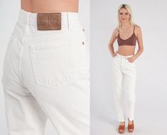 "Vintage 90s jeans by Calvin Klein in white denim with a high waist and a slim cut leg. Please see measurements and condition below. Every garment we sell is authentic vintage and one-of-a-kind! You will receive the exact item photographed. Condition: Very good vintage. Has a couple faint spots that should come out with cleaning. Best fits women's: Labelled size 6. Waist measures 26\". Tag: Calvin Klein Material:  Cotton MEASUREMENTS Taken from seam to seam while the garment is lying flat. Doubl Fitted White Jeans With Belt Loops, White Fitted Jeans With Belt Loops, White 90s Jeans For Spring, White Denim Bottoms In 90s Style, 90s White Denim Bottoms, Retro High Rise White Jeans, Vintage High Waist White Pants, White High-rise Retro Jeans, Vintage High-waist White Pants