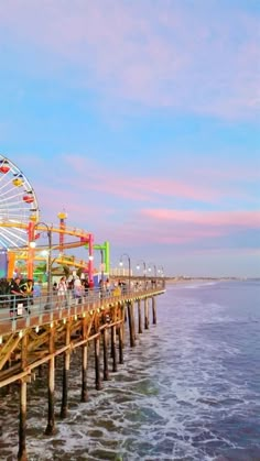 a ferris wheel sitting on top of a pier next to the ocean