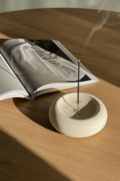 an open book sitting on top of a wooden table next to a small white object