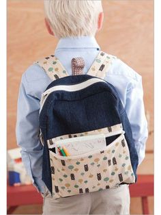 a young boy with a back pack and pencils in his pocket is looking at the wall