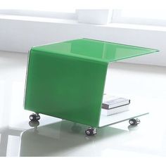 a green table sitting on top of a white floor next to a book shelf and window