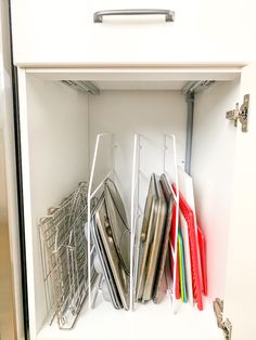 an organized kitchen cabinet with utensils and folders in the bottom drawer area