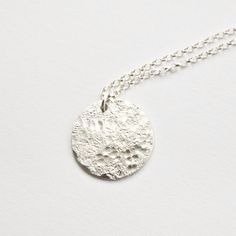 This silver moon necklace features a solid sterling silver disc that I have textured with a hammer by hand so each one will be completely unique. The texture gives a really interesting moonscape effect with a distressed stone imprint and rounded dimple pattern. It is the perfect pendant for layering with other simple jewellery for a minimal, modern look. The disc measures around 20mm diameter and the sterling silver chain comes in a choice of lengths. I textured it by hammering it on a rough sto Silver Moon Necklace With Coin Pendant, Silver Moon-shaped Jewelry With Coin Pendant, Nickel-free Sterling Silver Round Coin Necklace, Hammered Sterling Silver Coin Necklace, Round Sterling Silver Hammered Coin Necklace, Hammered Round Sterling Silver Coin Necklace, Engraved Sterling Silver Round Coin Necklace, Engraved Sterling Silver Coin Necklace, Silver Moon Phase Disc Jewelry