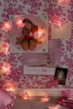 there is a pink wall with pictures and lights on it that have been placed in the corner