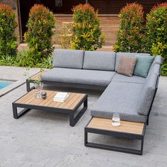 a couch and coffee table sitting on top of a brick patio next to a swimming pool