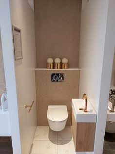 a white toilet sitting next to a bathroom sink under a faucet in a bathroom