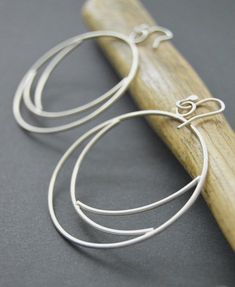 Silver hoops made from sterling silver 16 gauge wire.  These Eclipse earrings were shaped and meticulously pieced together by hand.  The hoops were tumbled for several hours to give them strength and durability, afterwards buffed to a brush finish.  One of my favorite designs!  An everyday statement earring that is unique and crafted with passion.~Length 2.25 inches~Width 2 inches~The earrings pictured are not the exact ones that you will receive, but a twin version will be duplicated with sligh Modern Hand Forged Circle Hoop Earrings, Modern Wire Wrapped Round Hoop Earrings, Handmade Minimalist Small Hoop Wrap Earrings, Sterling Silver Circle Hoop Earrings With Ear Wire, Sterling Silver Hoop Earrings With Ear Wire, Sterling Silver Open Circle Hoop Earrings For Pierced Ears, Modern Wire-wrapped Round Hoop Earrings, Modern Handmade Sterling Silver Hoop Earrings, Hand Forged Sterling Silver Round Hoop Earrings