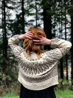 a woman standing in the woods with her hands on her head