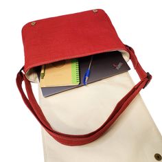 a red and white purse with some books in it's pocket on the side