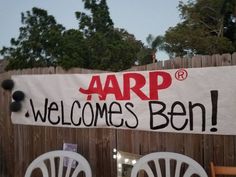 a sign that says aarp welcomes ben on the side of a wooden fence