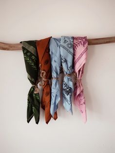 five scarves are hanging on a wooden stick