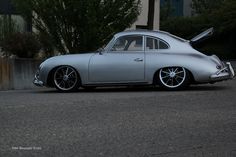 an old silver car parked on the side of the road