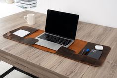 an open laptop computer sitting on top of a wooden desk next to a coffee cup