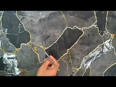 a person is using scissors to paint the surface of a large piece of art that looks like marble