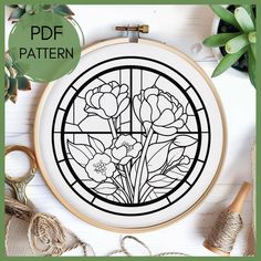 a cross stitch pattern with flowers in a round frame on top of a white table