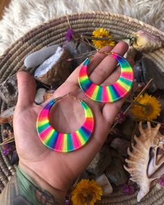 a pair of rainbow colored hoop earrings sitting on top of a basket filled with flowers