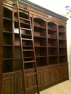 a large wooden bookcase with two ladders on it's sides and shelves in the middle