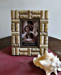 a photo frame made out of wine corks with a seashell on the table