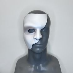 a white mask on top of a gray mannequin's head in front of a wall