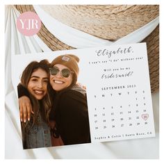 two women are posing for a photo in front of a calendar with the date on it