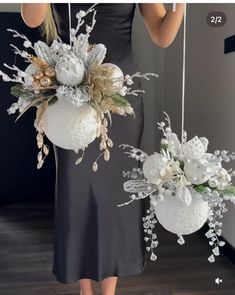 two white vases with flowers and greenery hanging from the ceiling in front of a mirror