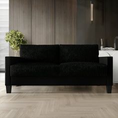 a black couch sitting on top of a hard wood floor next to a white cabinet