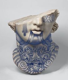 a blue and white vase with a face on it